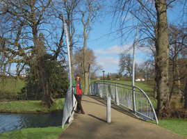 PITTVILLE PEDESTRIAN COMMUNITY BRIDGE - 2012 - Pittville Park, Cheltenham - Span 21.5M (70’). Client: Cheltenham Borough Council. END VIEW SHOWING CURVED BULRUSH ENTRANCE POSTS. Designed  & made by Christopher Lisney (with community groups input, & large scale fabrication, Longhope Welding). Copyright Chistopher Lisney 2014 - All Rights reserved by DESIGN PROTECT